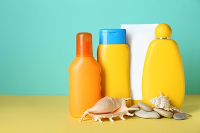 Different suntan products, seashells and stones on color background