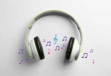 Image of Headphones, colorful music notes and treble clef on white background, top view