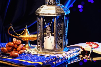 Arabic lantern, Quran, misbaha, Aladdin magic lamp, dates and folded prayer mat on mirror surface at night