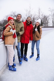 Image of Group of friends near fence at outdoor ice rink