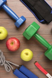 Flat lay composition with dumbbells on wooden table
