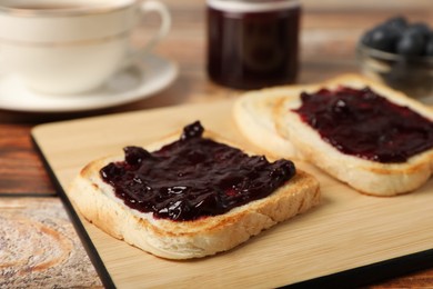 Photo of Delicious toasts with blueberry jam on wooden table, closeup