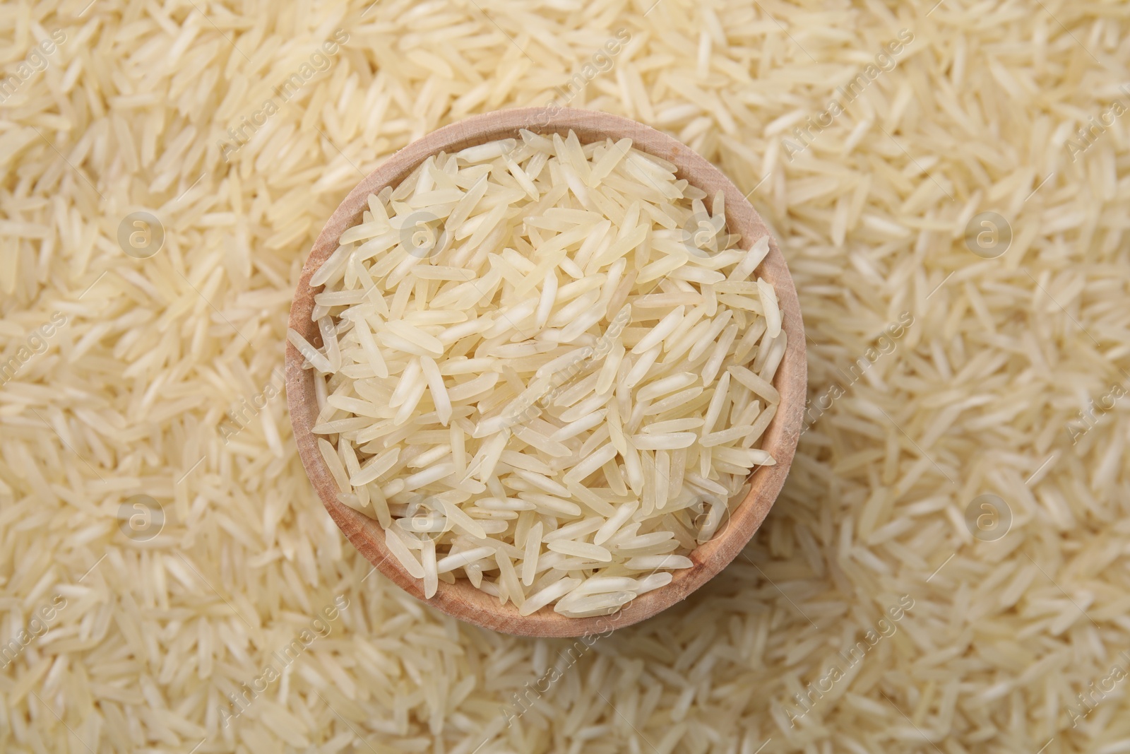 Photo of Bowl and raw rice as background, top view