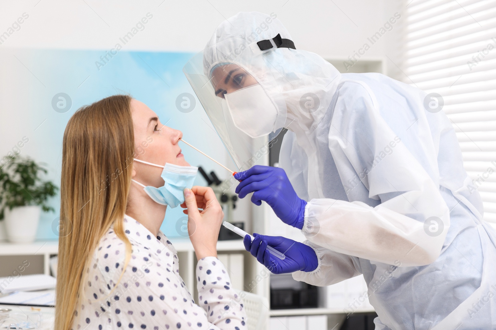 Photo of Laboratory testing. Doctor in uniform taking sample from patient's nose with cotton swab at hospital