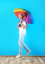 Man with rainbow umbrella near color wall