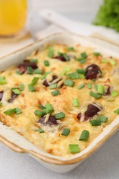 Photo of Tasty sausage casserole with green onions in baking dish on white table, closeup