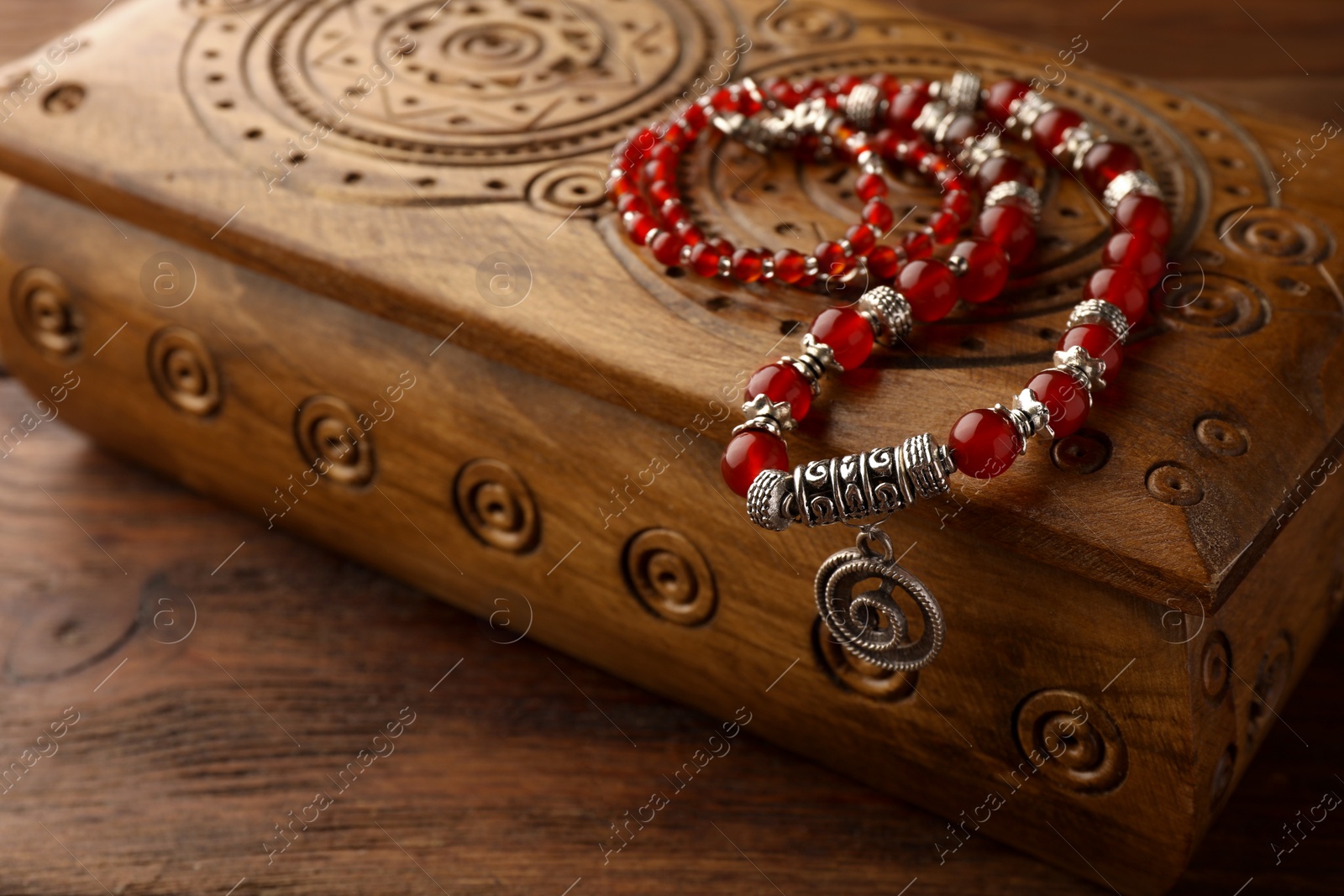 Photo of Beautiful necklace with gemstones and wooden jewelry box on table