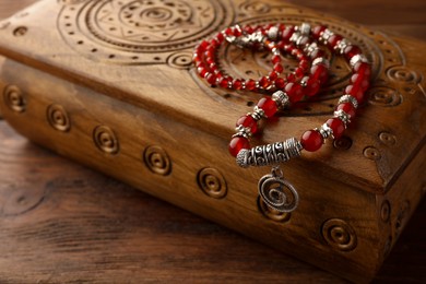 Beautiful necklace with gemstones and wooden jewelry box on table