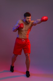 Photo of Man in boxing gloves fighting on color background