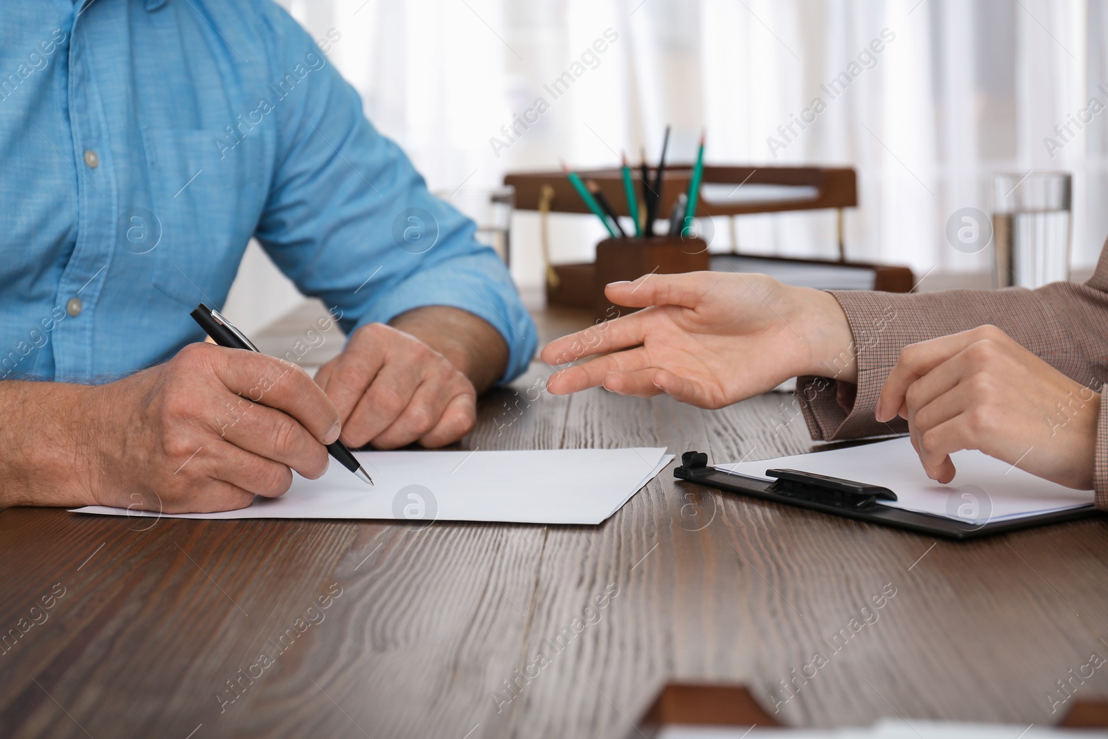 Photo of Senior man signing document in lawyer's office