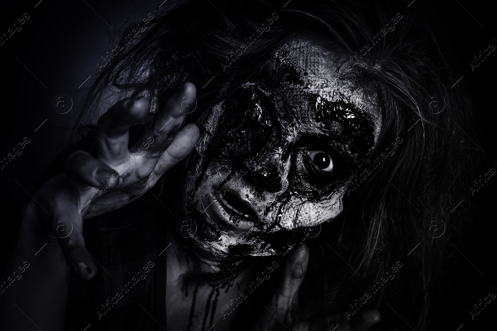 Photo of Scary zombie on dark background, black and white effect. Halloween monster