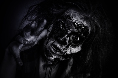 Photo of Scary zombie on dark background, black and white effect. Halloween monster