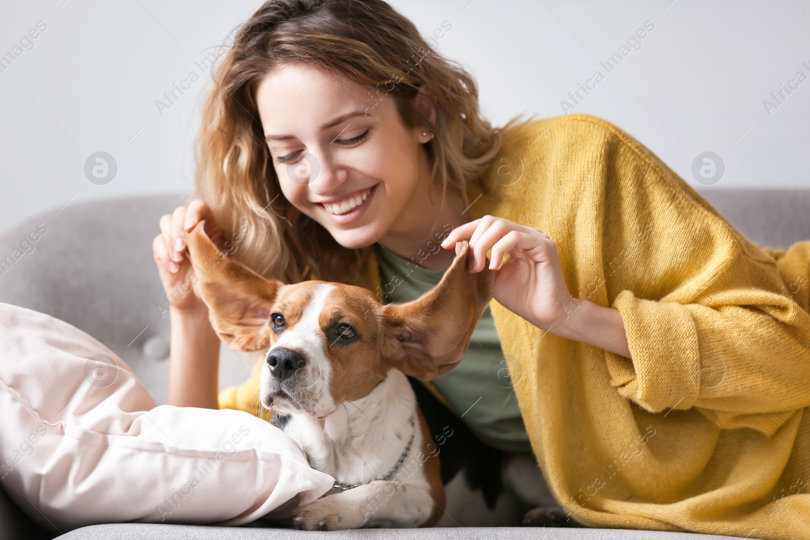 Photo of Young woman with her dog resting on sofa at home