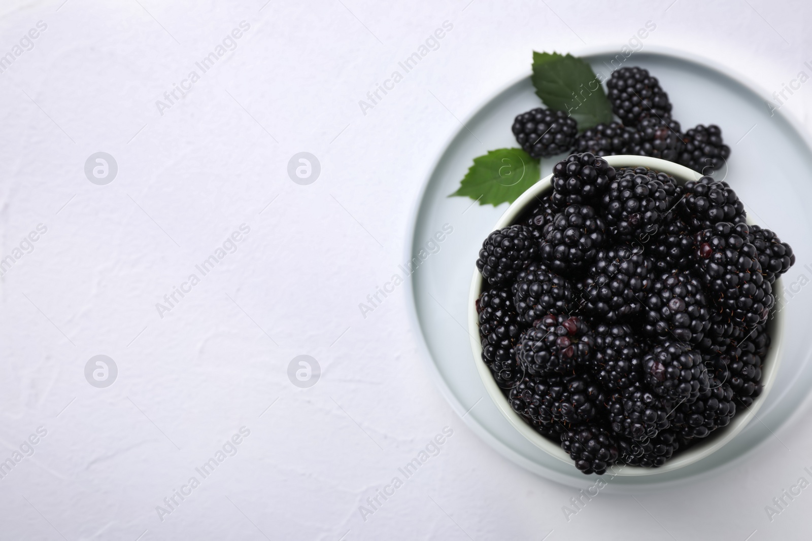 Photo of Fresh ripe blackberries on white table, top view. Space for text