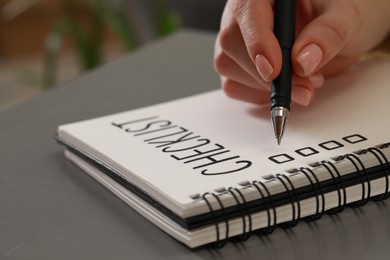 Woman filling Checklist with pen at grey table, closeup