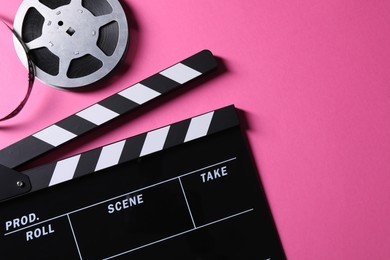 Photo of Clapperboard and film reel on pink background, flat lay. Space for text