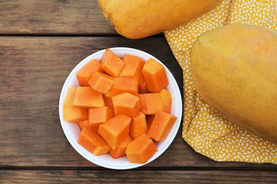 Tasty whole and cut papaya fruits on wooden table, flat lay