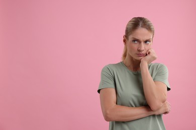 Resentful woman on pink background. Space for text
