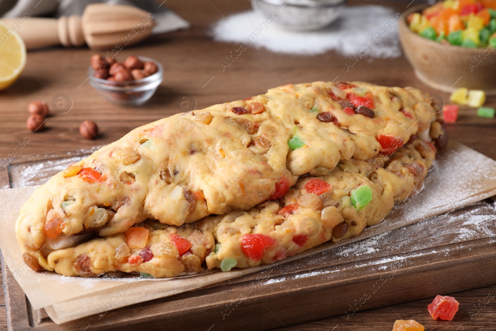 Photo of Unbaked Stollen with candied fruits and raisins on wooden table, closeup