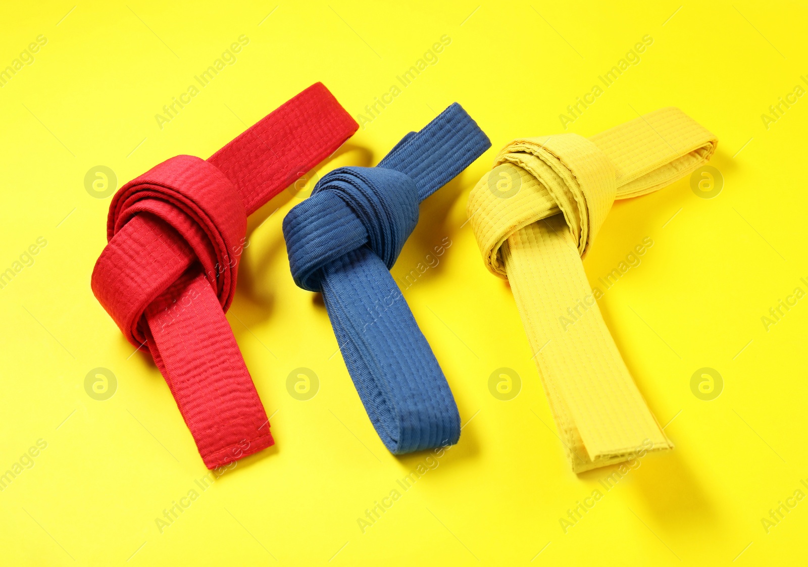 Photo of Colorful karate belts on yellow background. Martial arts uniform