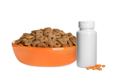 Dry pet food in feeding bowl and bottle with vitamin pills on white background