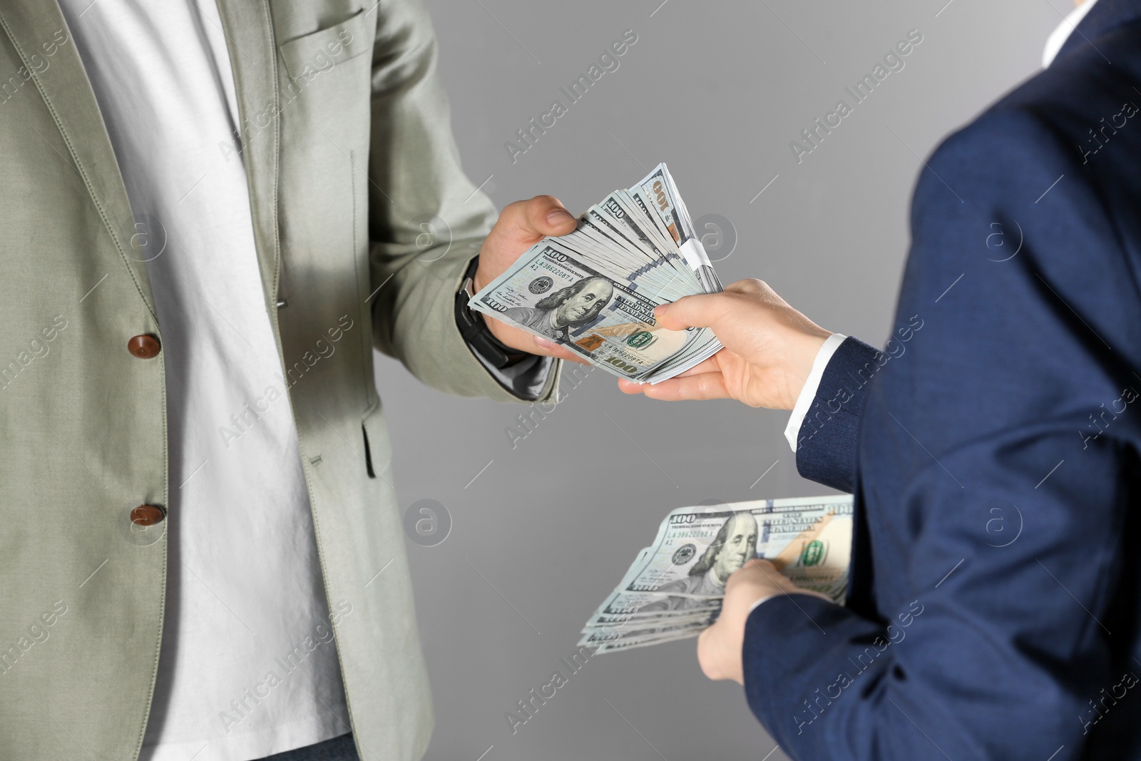 Photo of Woman giving bribe money to man on grey background, closeup
