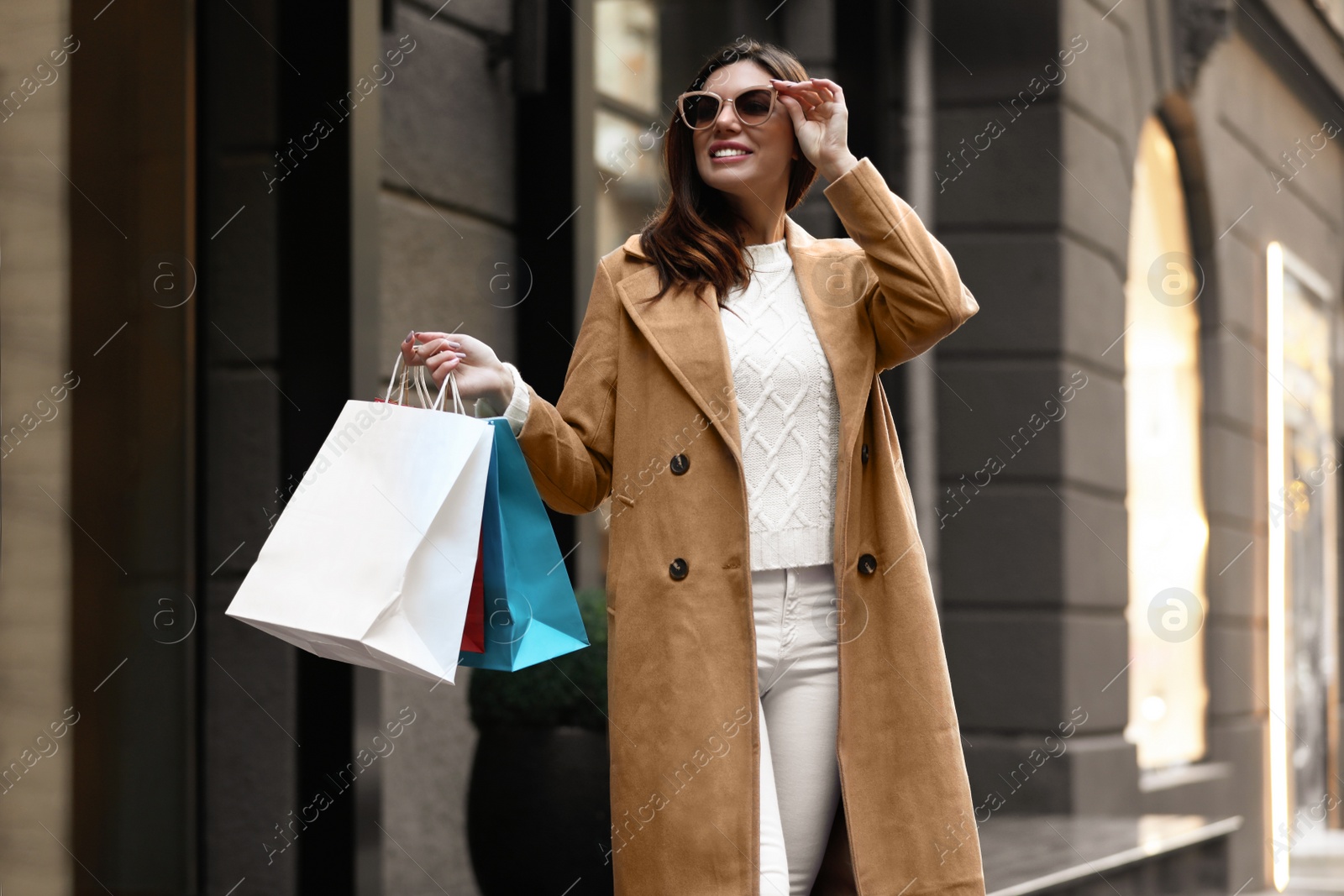 Photo of Beautiful young woman with shopping bags on city street