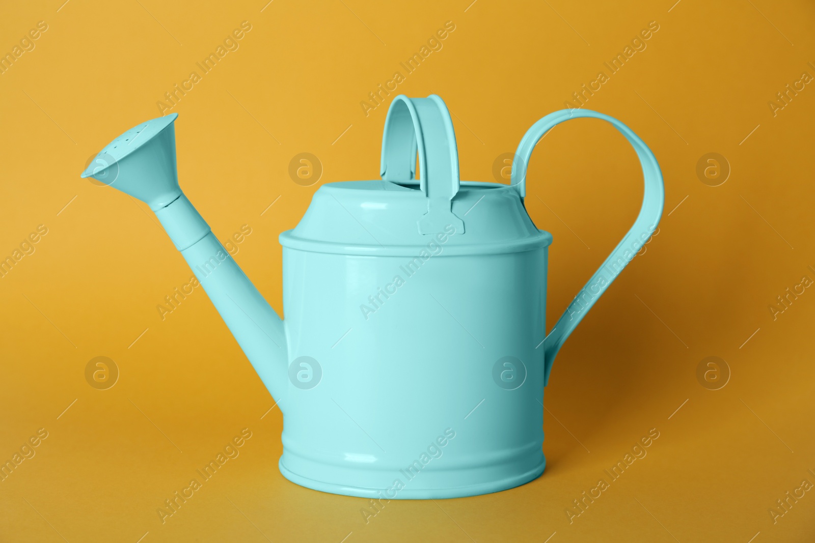 Photo of Turquoise metal watering can on yellow background