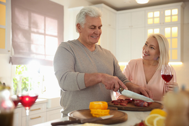 Photo of Mature couple cooking food together in kitchen