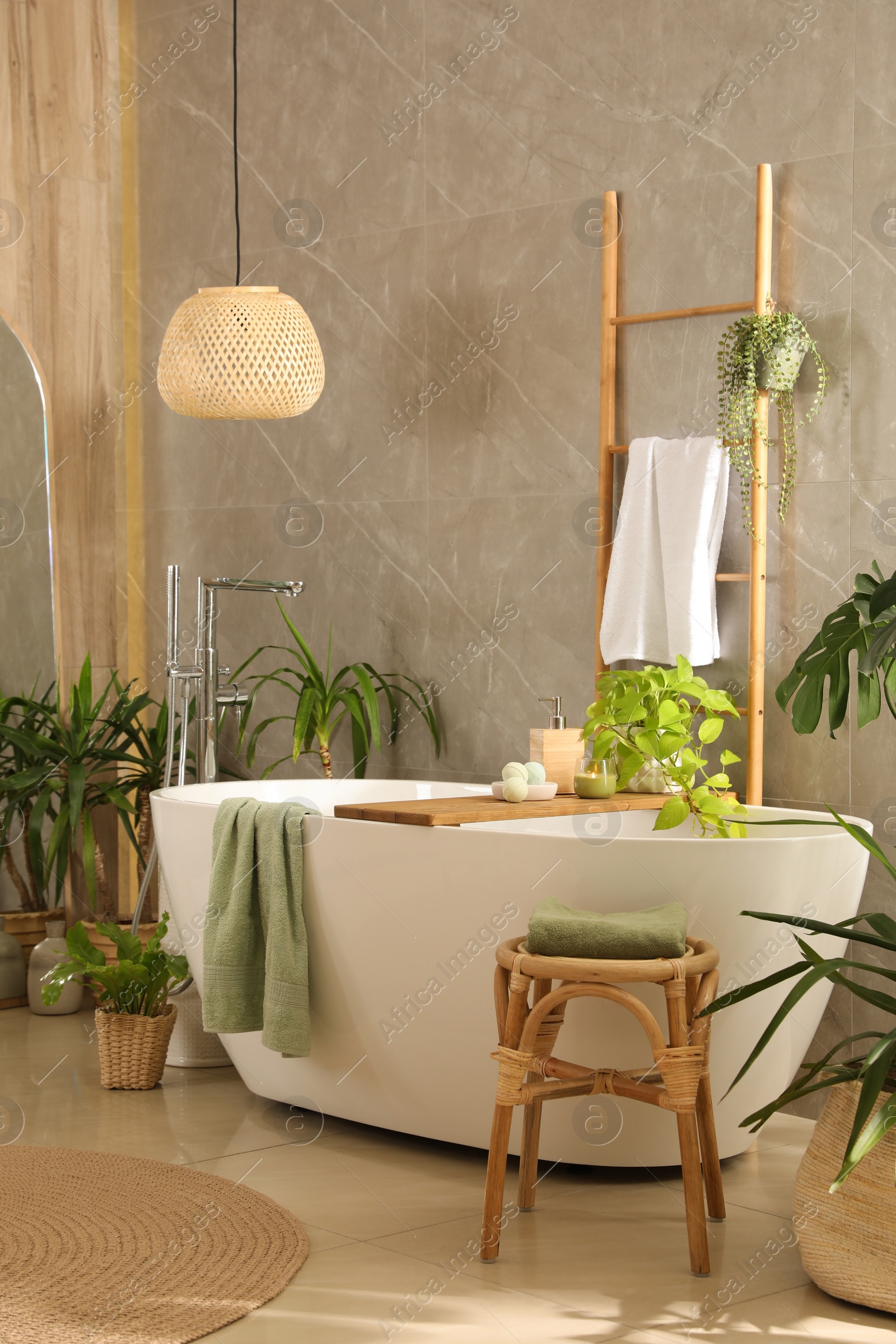 Photo of Modern white tub and beautiful green houseplants in bathroom. Interior design