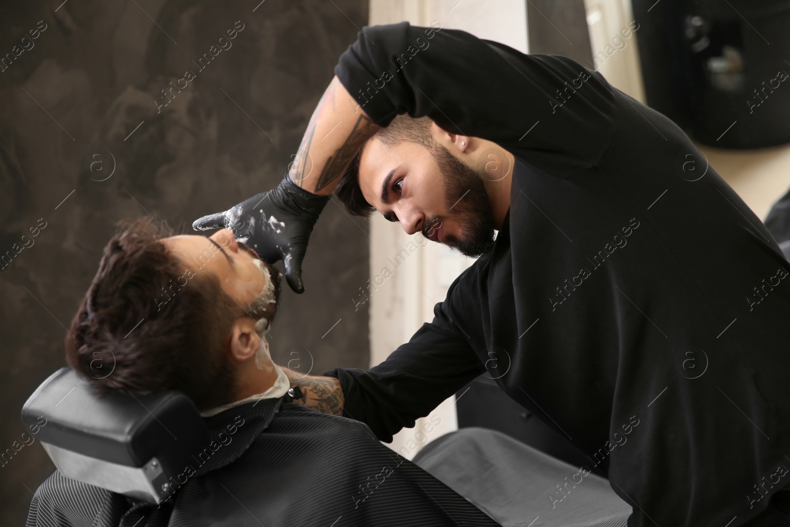 Photo of Hairdresser working with client at barbershop. Professional shaving service