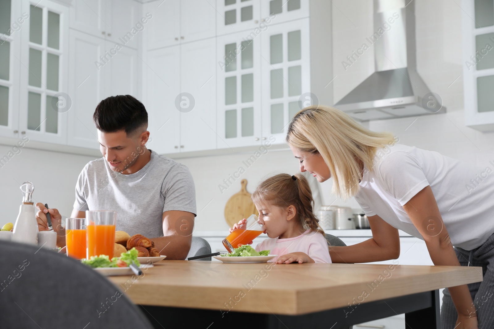 Photo of Happy family having breakfast together at table in modern kitchen