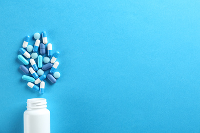 Flat lay composition with pills on light blue background. Space for text