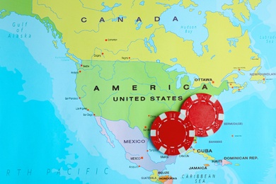 Photo of Red casino chips near USA on world map, top view