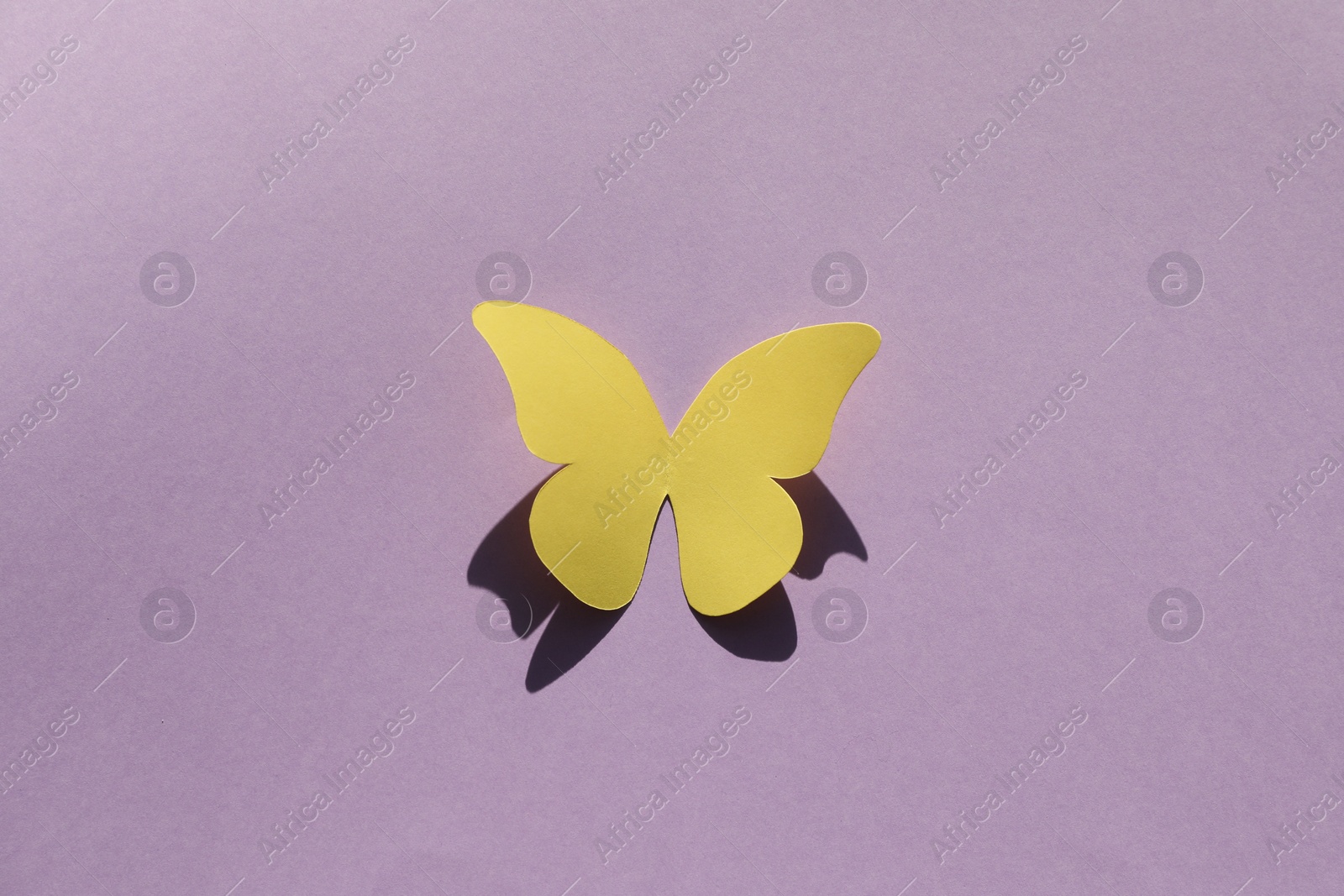 Photo of Yellow paper butterfly on violet background, top view