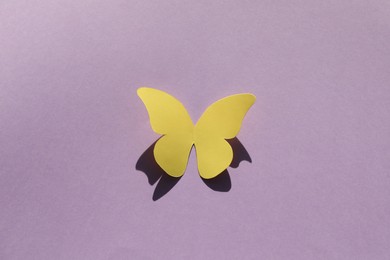 Yellow paper butterfly on violet background, top view