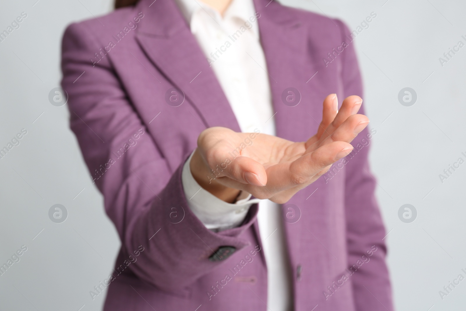 Photo of Young woman against light grey background, focus on hand