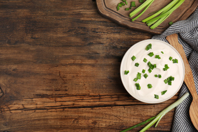 Photo of Fresh sour cream with onion on wooden table, flat lay. Space for text