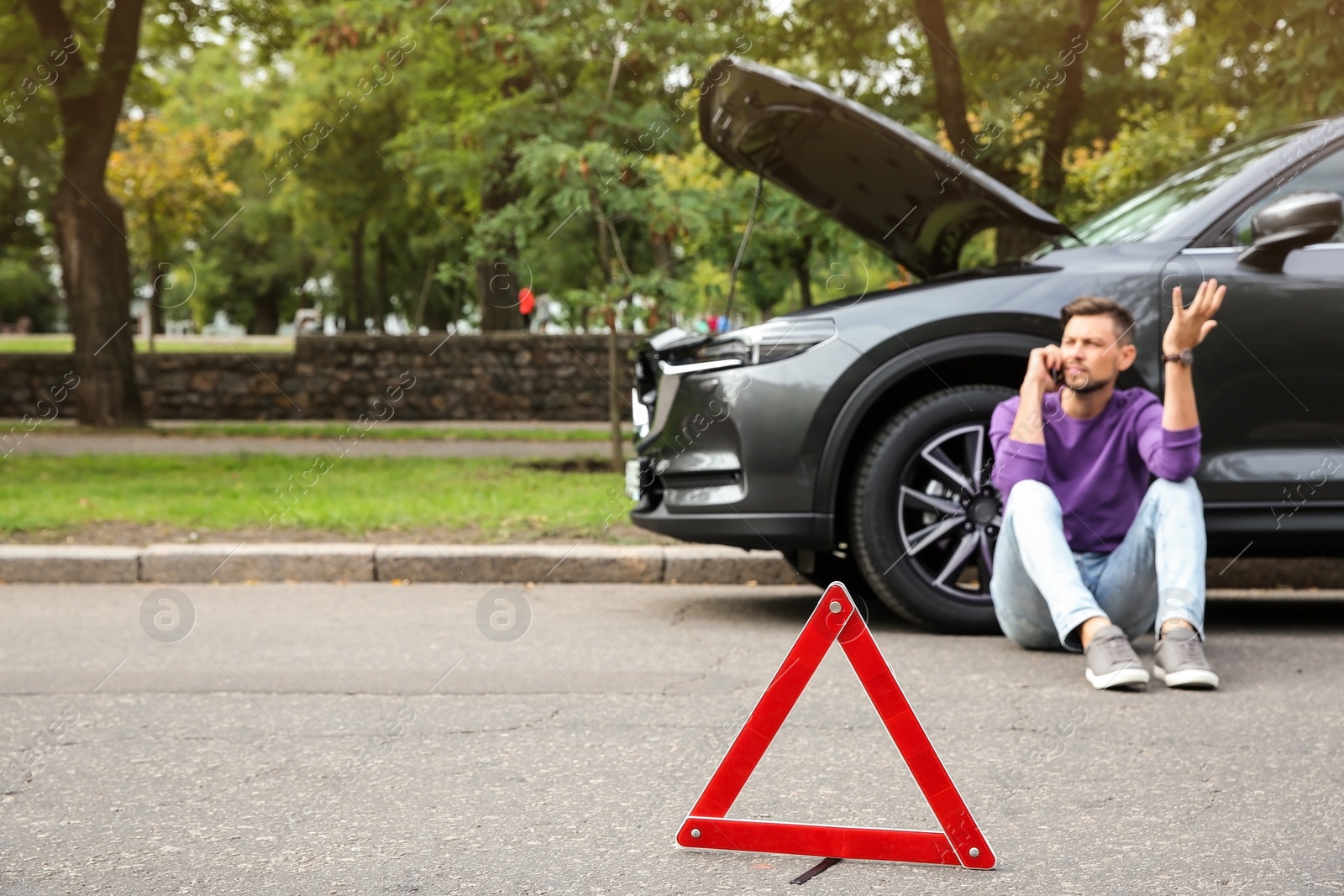 Photo of Emergency stop sign and man near broken car on background