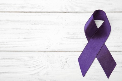 Photo of Purple ribbon on white wooden background, top view with space for text. Domestic violence awareness