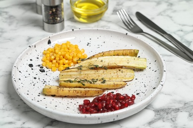 Photo of Baked white carrot with sweet corn and pomegranate seeds on marble table, closeup