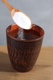 Adding baking soda into water at wooden table