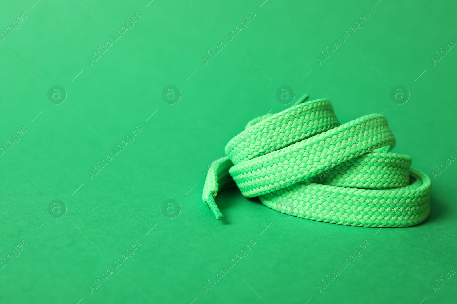 Photo of Mint shoe lace on green background. Space for text