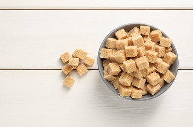 Brown sugar cubes on white wooden table, flat lay. Space for text