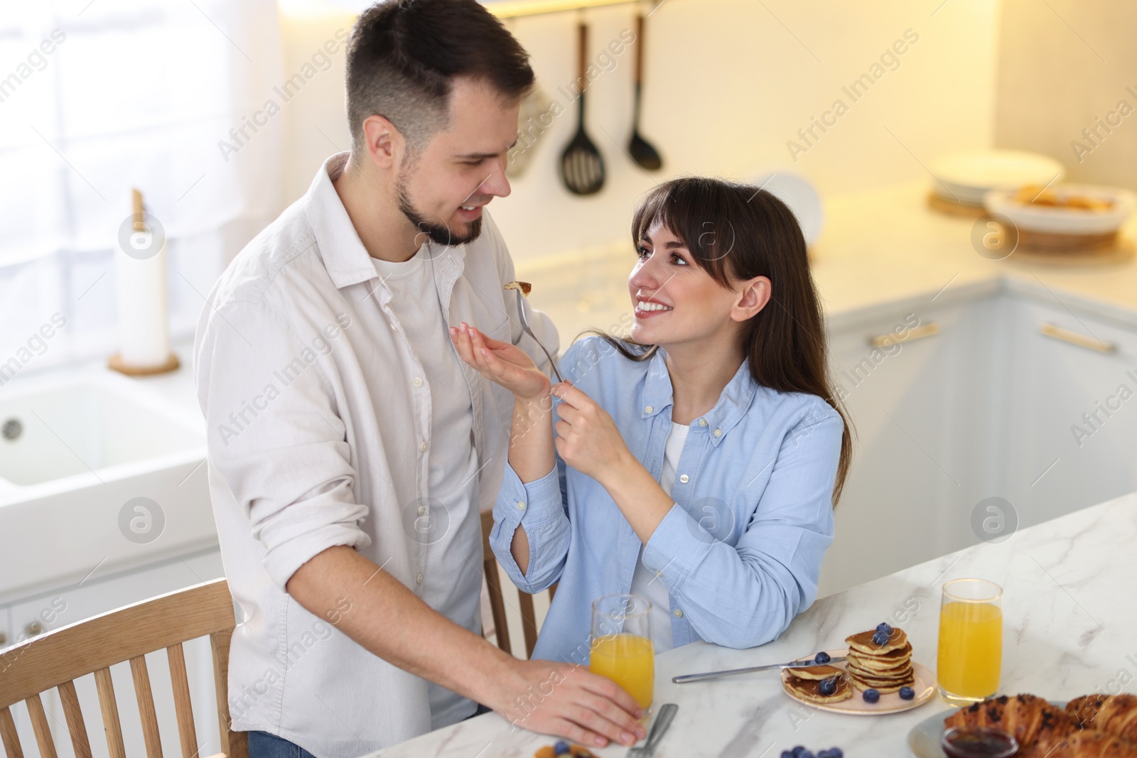 Photo of Tasty breakfast. Happy wife feeding her husband at home