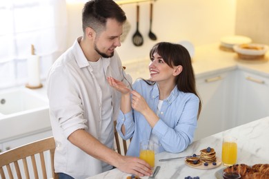 Photo of Tasty breakfast. Happy wife feeding her husband at home