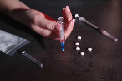 Photo of Addicted woman at table with different drugs, closeup