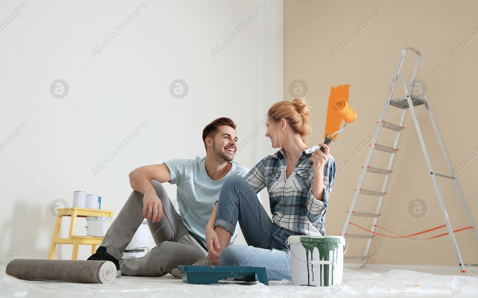 Photo of Happy couple with paint planning home repair indoors