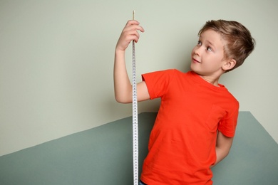 Photo of Little boy measuring his height on color background