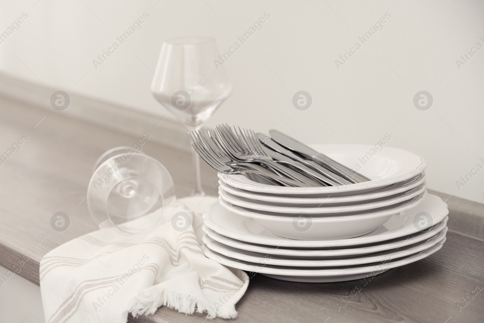 Photo of Set of clean dishware, cutlery and wineglasses on table indoors